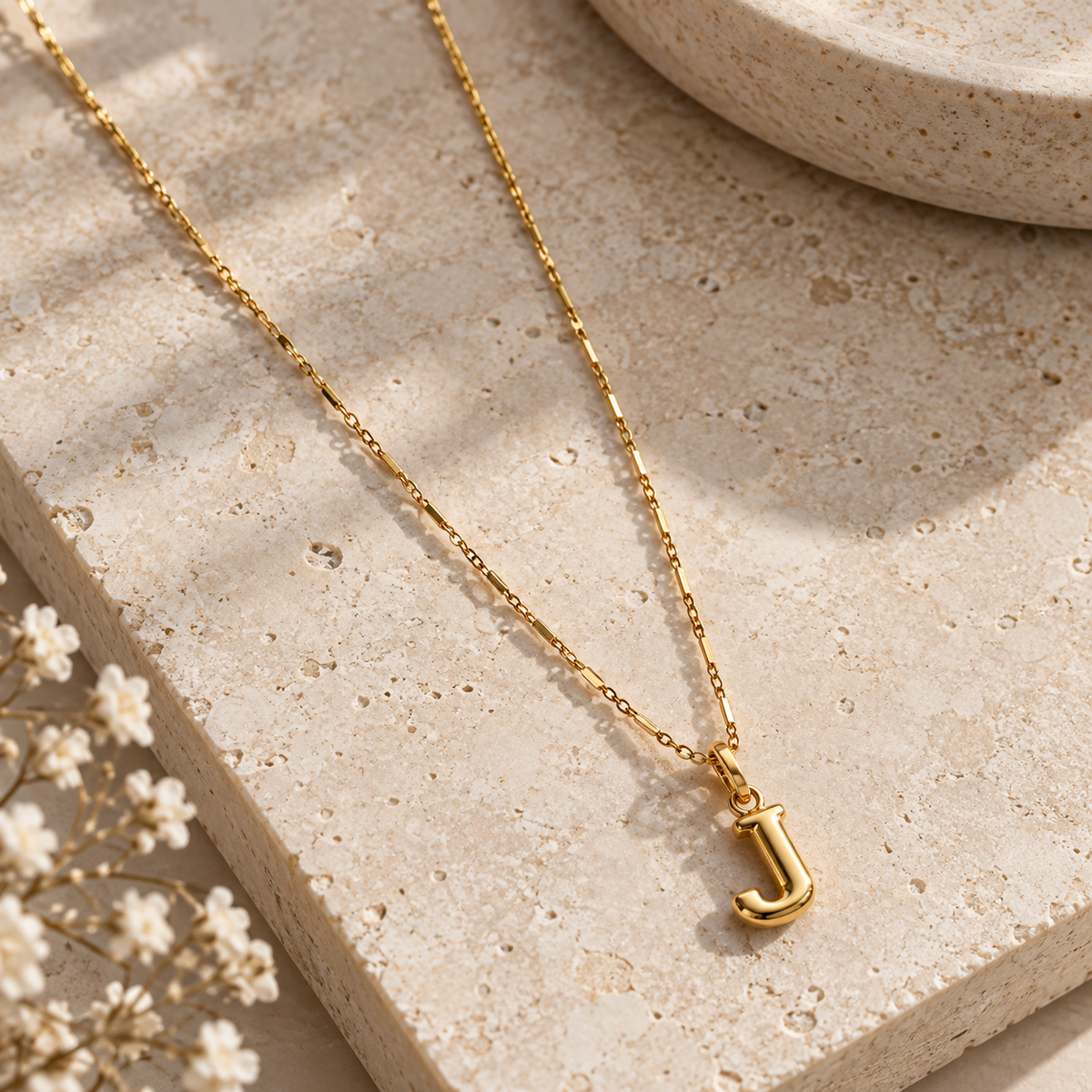 Colgante con inicial dorado sobre piedra
